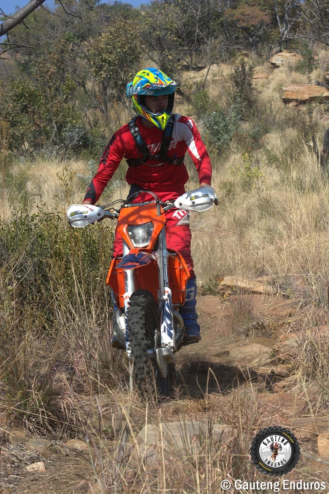 Rider riding through tall dry grass on a rocky line